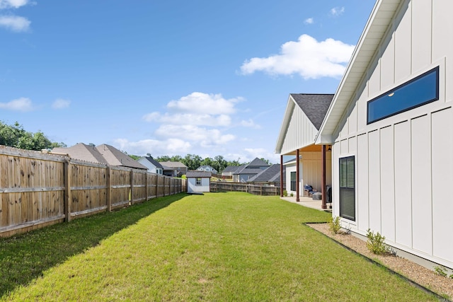 view of yard with a patio area, a fenced backyard, a storage unit, and an outbuilding