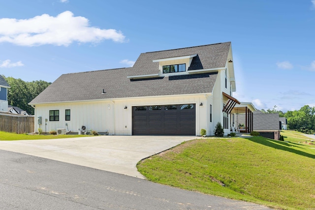 modern farmhouse with a garage, a front yard, concrete driveway, and roof with shingles