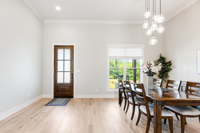 dining room featuring light wood finished floors, baseboards, crown molding, and an inviting chandelier