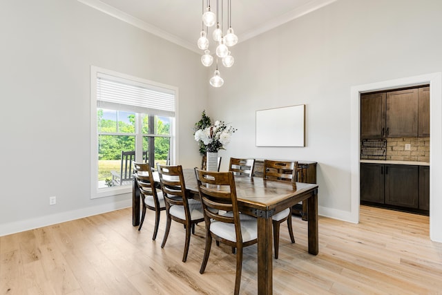 dining area featuring baseboards, crown molding, and light wood finished floors