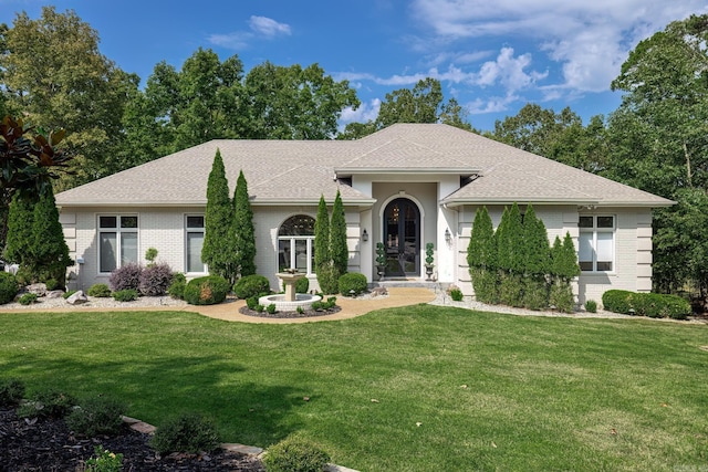 ranch-style home featuring brick siding, roof with shingles, and a front yard