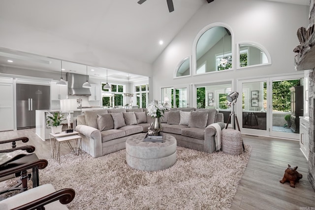 living room featuring high vaulted ceiling, a healthy amount of sunlight, ceiling fan, and light wood finished floors