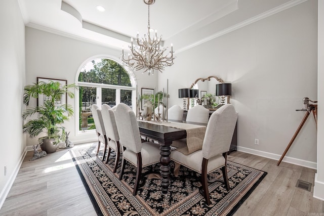 dining area with a tray ceiling, visible vents, and light wood finished floors