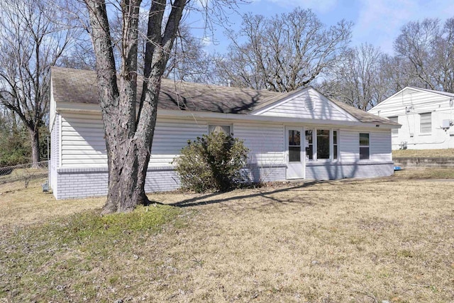 rear view of house with a yard, fence, and a shingled roof