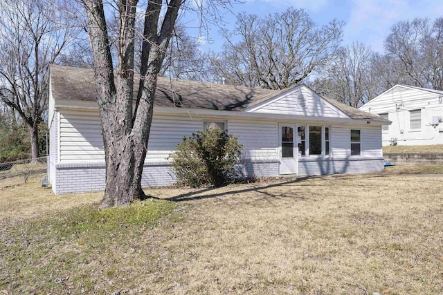 rear view of house featuring a yard, roof with shingles, and fence