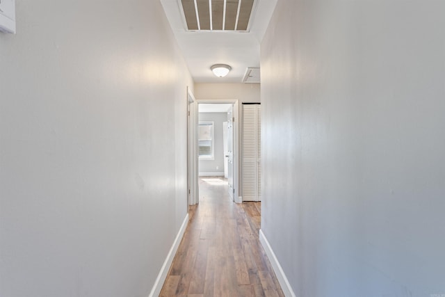 hallway featuring wood finished floors, visible vents, and baseboards