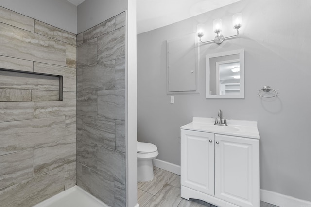 bathroom with toilet, baseboards, a shower, and vanity