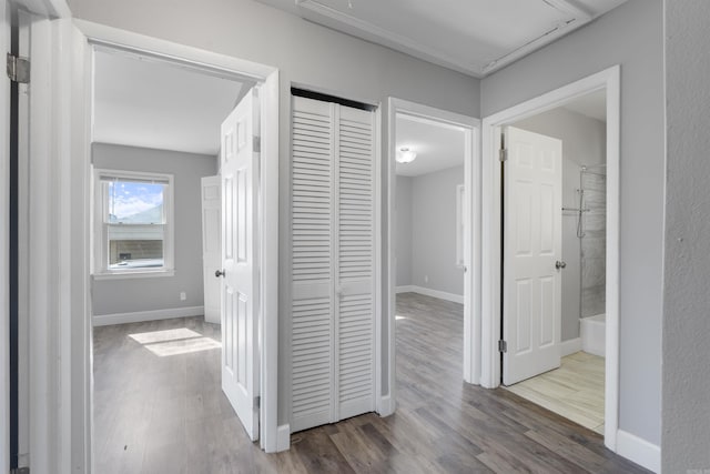 corridor with attic access, baseboards, and wood finished floors