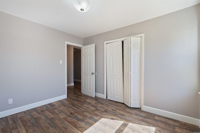 unfurnished bedroom featuring a closet, dark wood finished floors, and baseboards