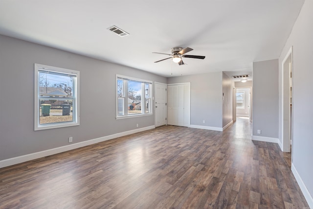 spare room with dark wood-style floors, baseboards, visible vents, and a ceiling fan