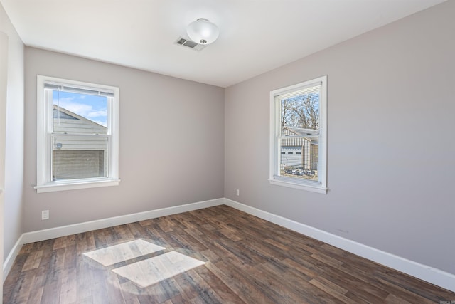 unfurnished room with dark wood-style floors, baseboards, and visible vents