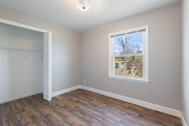 unfurnished bedroom with a closet, dark wood finished floors, and baseboards