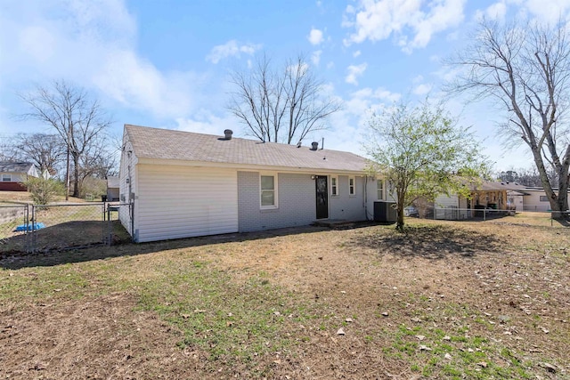 back of property featuring a yard, a fenced backyard, cooling unit, and brick siding