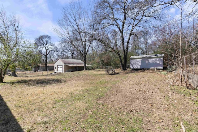 view of yard featuring a garage, an outbuilding, fence, and a shed