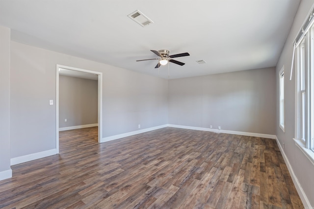 unfurnished room featuring dark wood-style floors, visible vents, ceiling fan, and baseboards