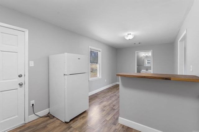 kitchen with visible vents, baseboards, wood finished floors, and freestanding refrigerator