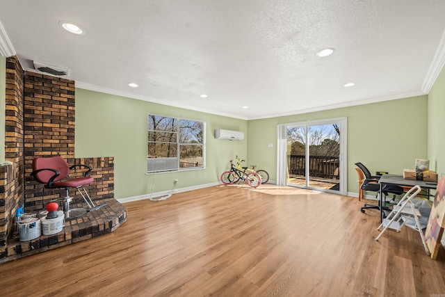 interior space with a textured ceiling, ornamental molding, an AC wall unit, and wood finished floors