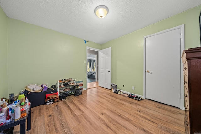 rec room featuring a textured ceiling, wood finished floors, and baseboards