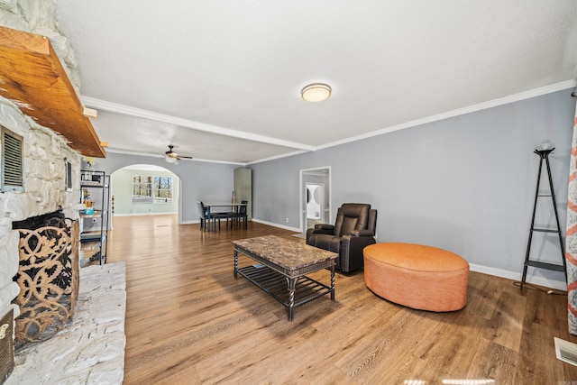 living room with baseboards, crown molding, arched walkways, and wood finished floors