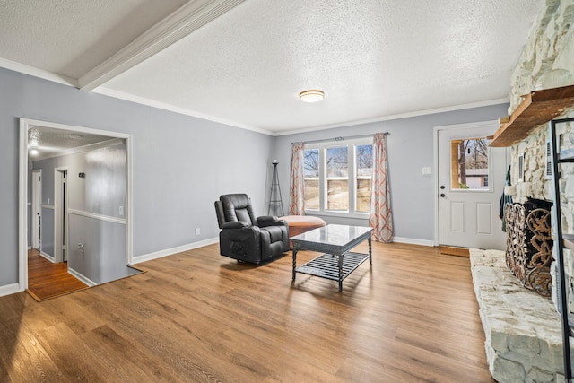 living area with light wood-style floors, plenty of natural light, crown molding, and a stone fireplace