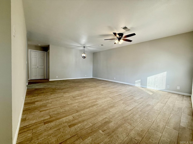 unfurnished room featuring baseboards, ceiling fan, visible vents, and wood finished floors