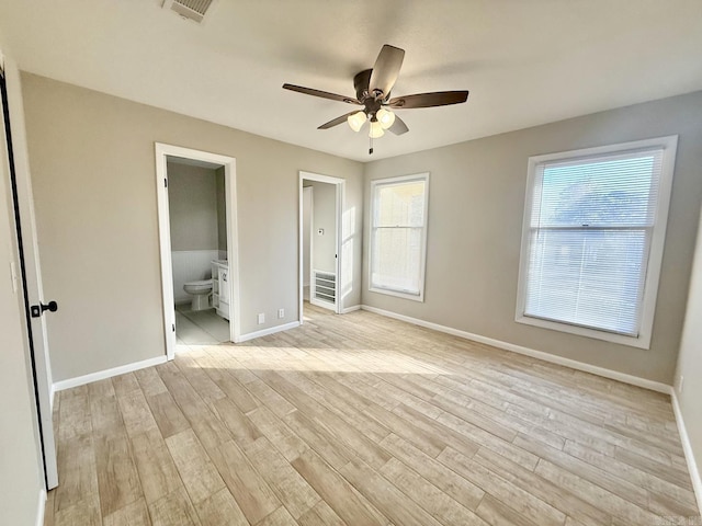 unfurnished bedroom with ensuite bathroom, light wood finished floors, visible vents, and baseboards