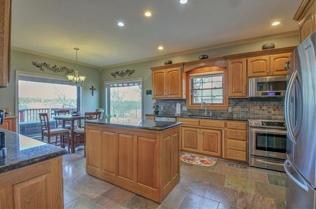 kitchen with backsplash, appliances with stainless steel finishes, ornamental molding, a kitchen island, and a sink