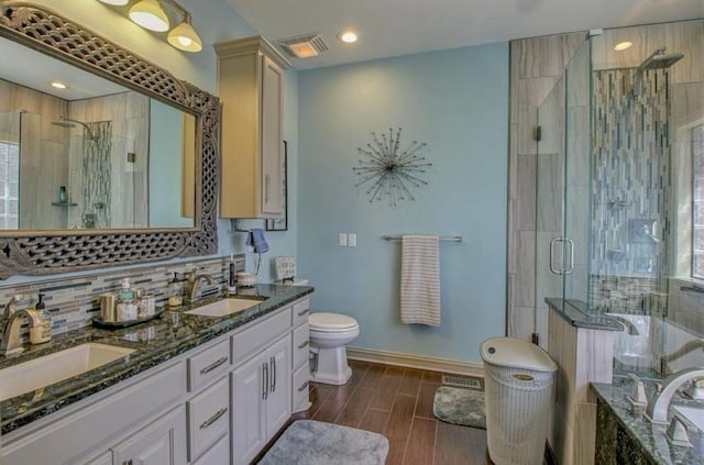 bathroom with a stall shower, backsplash, and a sink