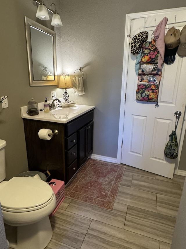 bathroom featuring toilet, baseboards, and vanity