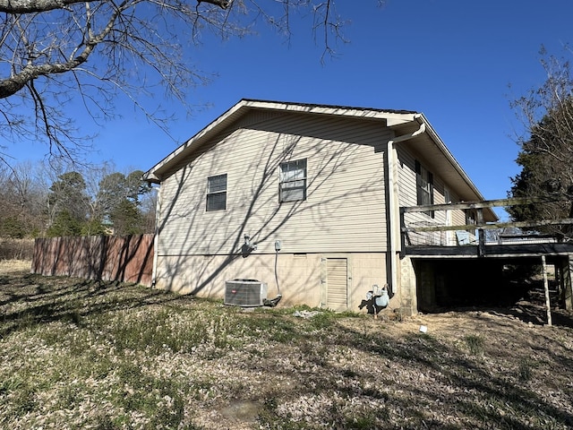 view of home's exterior with fence, a wooden deck, and central AC unit