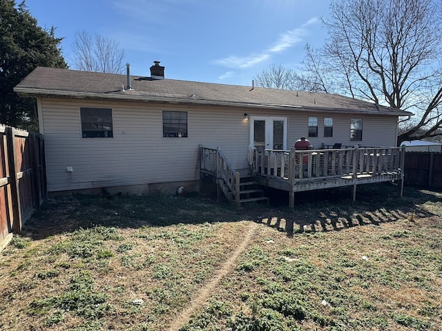 back of property with a fenced backyard, a chimney, a deck, and french doors