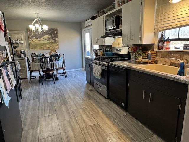 kitchen featuring a textured ceiling, a notable chandelier, a sink, range hood, and black appliances