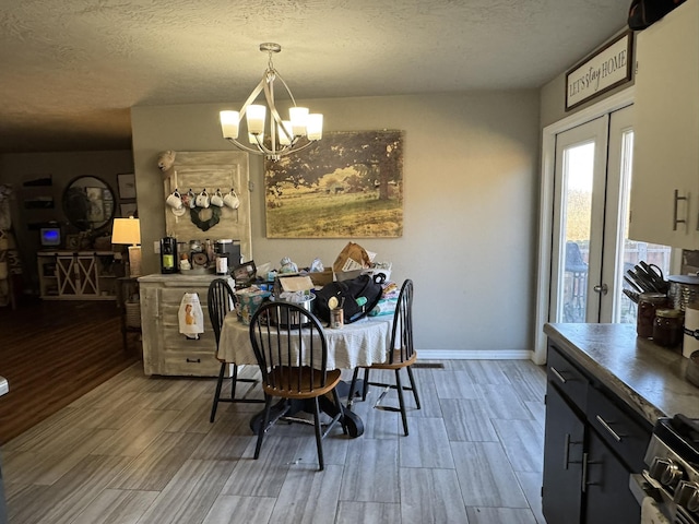 dining space featuring a chandelier, wood finish floors, a textured ceiling, and baseboards