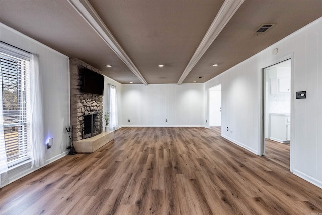 unfurnished living room with visible vents, a fireplace, baseboards, and wood finished floors