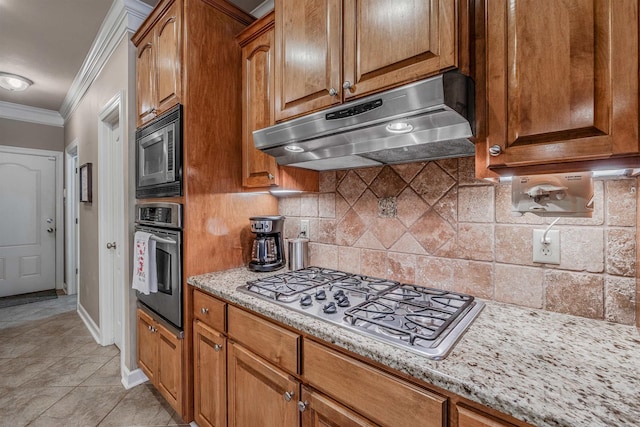 kitchen with brown cabinets, stainless steel appliances, tasteful backsplash, ornamental molding, and under cabinet range hood