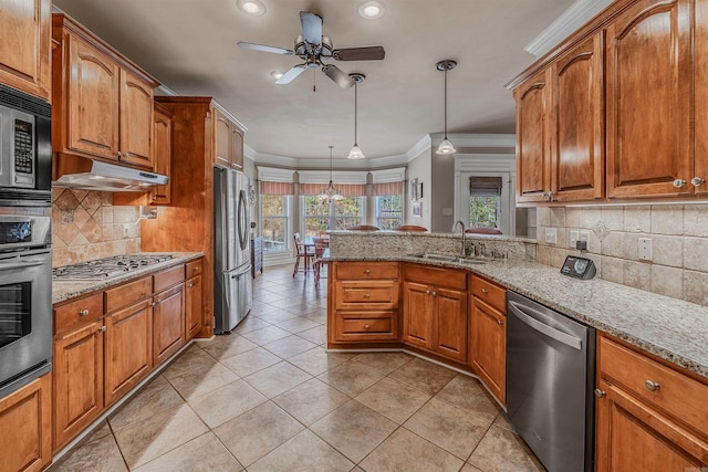 kitchen featuring stainless steel appliances, brown cabinets, a sink, and ornamental molding