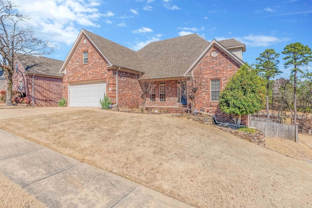 view of front of home with roof with shingles, brick siding, driveway, and fence