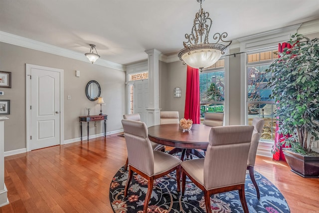 dining room with crown molding, a wealth of natural light, decorative columns, and light wood-style flooring