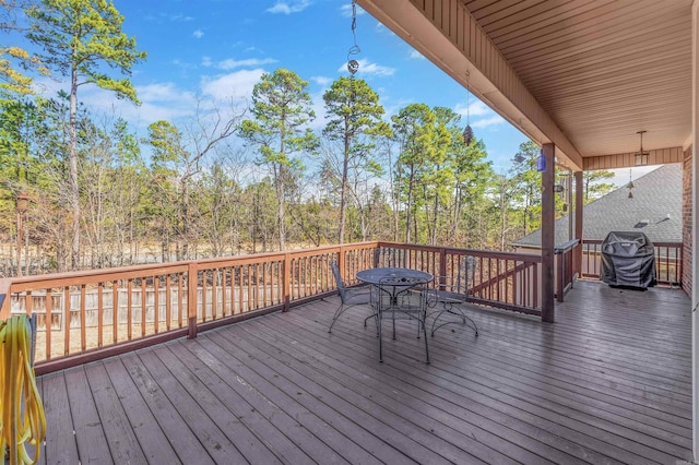 wooden terrace with outdoor dining space and a grill