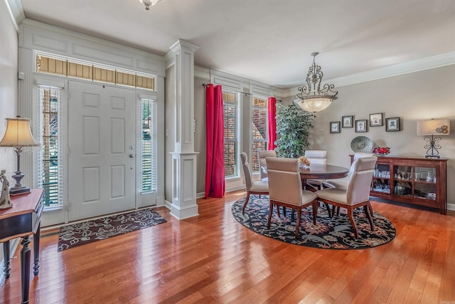 dining room featuring hardwood / wood-style flooring, ornamental molding, and ornate columns