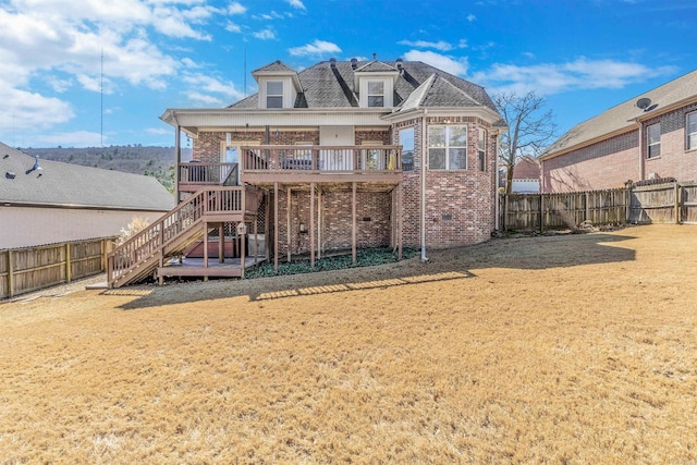 rear view of property with a yard, a fenced backyard, stairs, and brick siding