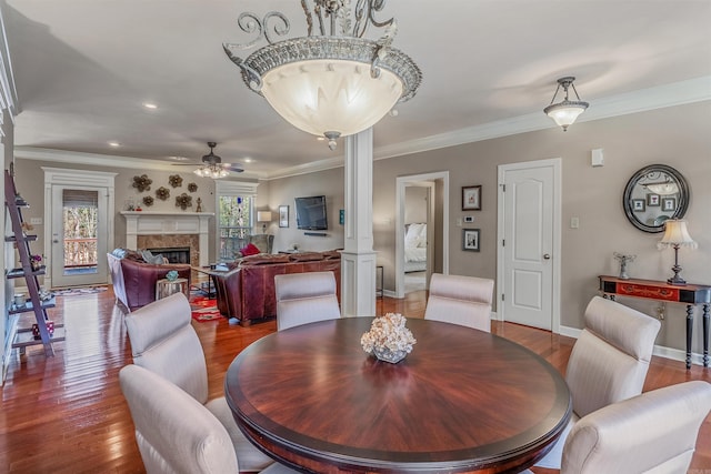 dining room with ornamental molding, a fireplace, and wood finished floors