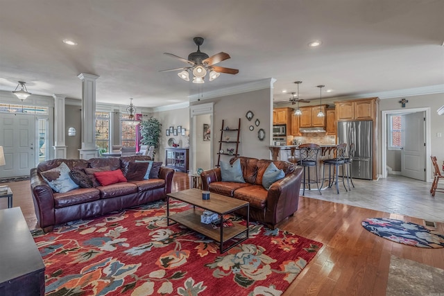 living room featuring light wood-type flooring, ornamental molding, plenty of natural light, and ornate columns