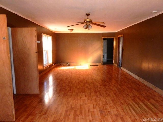 unfurnished room with ceiling fan, ornamental molding, wood finished floors, and baseboards