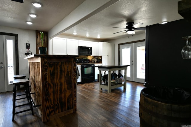 kitchen featuring white cabinets, dark wood-type flooring, a textured ceiling, french doors, and black appliances