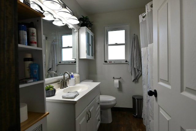 bathroom with toilet, baseboards, wood finished floors, and vanity