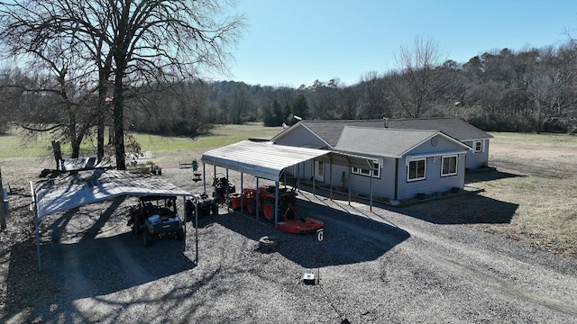 view of front of home with a carport, driveway, and a view of trees