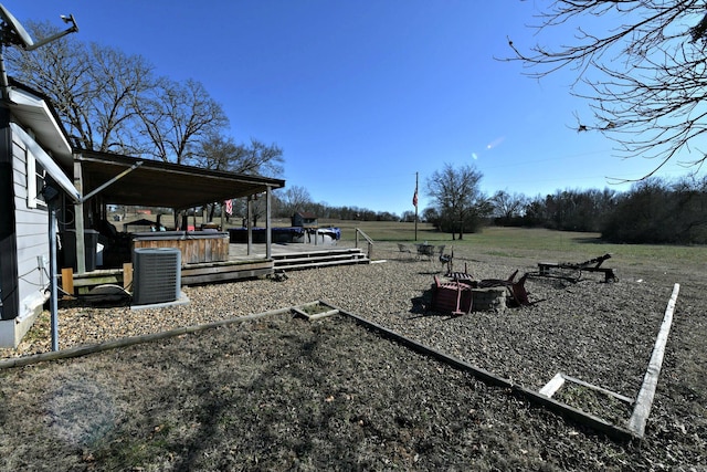 view of yard featuring a fire pit, cooling unit, a wooden deck, and a hot tub