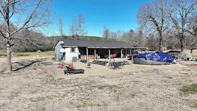 rear view of property featuring a deck, a greenhouse, an outdoor structure, and central air condition unit