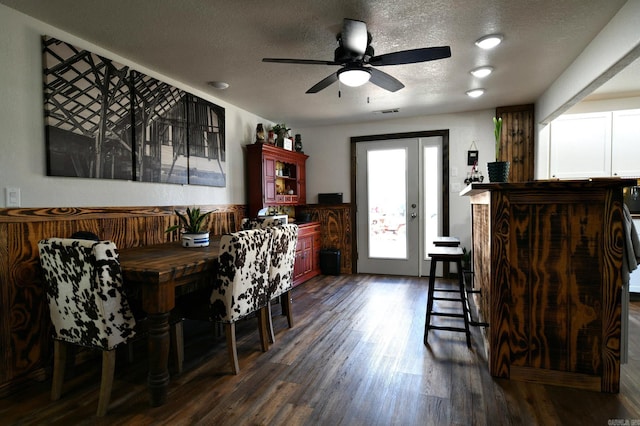 dining area featuring a textured ceiling, ceiling fan, and dark wood-style flooring